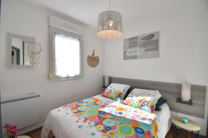 um quarto com uma cama com lençóis coloridos e uma janela em Point d'or L21 - Hossegor appartement 4 personnes plage piscine em Soorts-Hossegor