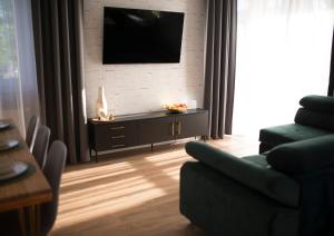 a living room with a couch and a tv on a wall at Apartament Wiśniewski - nad Jeziorem Drwęckim in Ostróda
