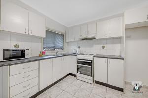 una cocina blanca con armarios y electrodomésticos blancos en Fairfield 1B Granny Flat Sleep up to 4 ppl, en Fairfield