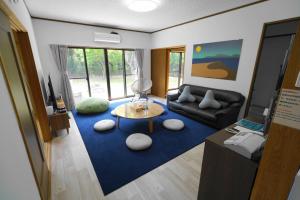 uma sala de estar com um sofá e um tapete azul em 一棟貸しの宿 OKAYADO em Oshima