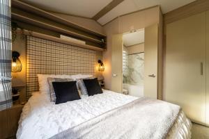 um quarto com uma grande cama branca com almofadas pretas em Wiswell View Lodge: Pendle View Holiday Park em Clitheroe