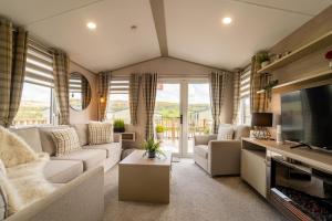a living room with a couch and a tv at Wiswell View Lodge: Pendle View Holiday Park in Clitheroe