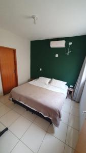 ein Schlafzimmer mit einem großen Bett und einer grünen Wand in der Unterkunft Quintal da Canastra - Room in São João Batista do Glória