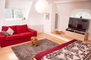Haus Koenige Hinterzarten في هينترتزارتن: غرفة معيشة مع أريكة حمراء وتلفزيون بشاشة مسطحة