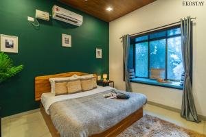 a bedroom with a bed and a green wall at EKO STAY- CASA POLO Villa in Alibaug