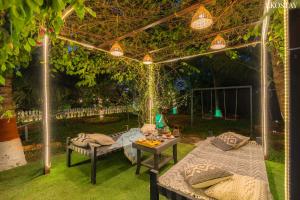 a pergola with two beds and a table in a garden at EKO STAY- CASA POLO Villa in Alibaug