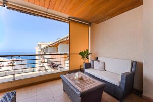 Un balcón con una silla, una mesa y una ventana en Ático en Balcón de Los Gigantes, en Puerto de Santiago