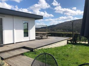 eine Holzterrasse mit einem Picknicktisch und einer Bank in der Unterkunft Chalet N°5 in Treignes