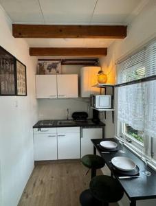 a kitchen with white cabinets and a table and chairs at Hello Noordwijk - Tiny House Dahliastraat 60 in Noordwijk