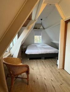 a bedroom with a bed and a chair in a attic at Hello Noordwijk - Tiny House Dahliastraat 60 in Noordwijk