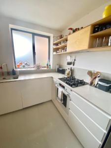 uma cozinha branca com um fogão e uma janela em Urban Oasis Chic 1BR Flat with Spacious Garden em Londres