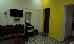 - un salon avec une télévision, un canapé et un miroir dans l'établissement FabExpress Guru Residency, à Kodaikānāl
