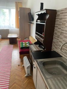 a kitchen with a sink and a living room at Retro Motel Mályi in Mályi