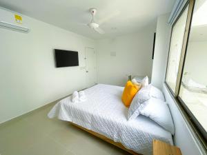 1 dormitorio con 1 cama con sábanas blancas y almohadas amarillas en Magico Apartaestudio con Piscina 1 Habitacion PR66A en Montería
