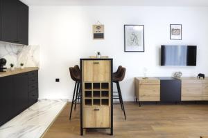 a kitchen with black cabinets and a tv on a wall at Tesla Sky Apartment in Ledine