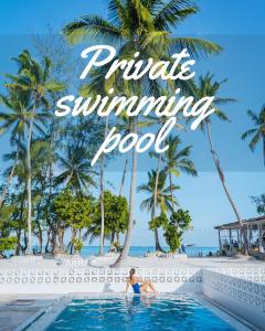 a woman sitting in a infinity pool at a resort with palm trees at Pili Pili Orient Beach Hotel in Bwejuu