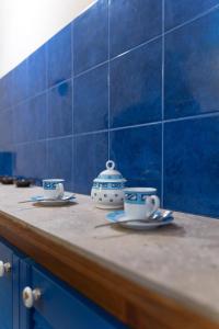 two cups and saucers on a counter with blue tiles at Burantì Guest House in Alghero