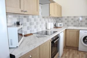 a kitchen with a sink and a washing machine at Sunrise Cottage in Llanddulas