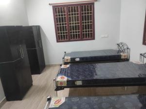 two beds in a room with a tv and a window at N k ladies PG in Chennai