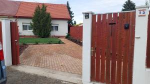 dom z czerwoną bramą i ceglanym podjazdem w obiekcie Dunakeszi Nap Apartman w mieście Dunakeszi