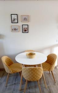 ein Tisch und zwei Stühle mit einem weißen Tisch und einigen Bildern in der Unterkunft Chez Sophie in Trouville-sur-Mer