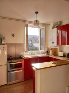 eine Küche mit roten Schränken und einem großen Fenster in der Unterkunft Chez Sophie in Trouville-sur-Mer