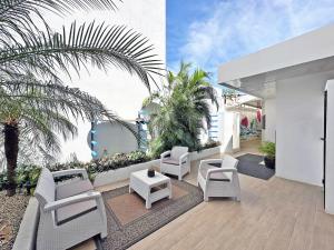 un patio con muebles blancos y palmeras en Surf Ranch Tamarindo en Tamarindo