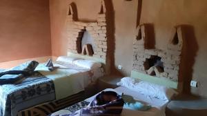 a room with two beds and a baby laying on the bed at Auberge Dinosaur Kem Kem in Tafraoute Sidi Ali