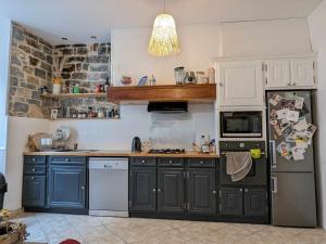 - une cuisine avec des armoires bleues et un réfrigérateur noir dans l'établissement Maison individuelle au cœur de Millau, à Millau
