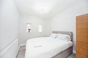a white bedroom with a bed with white sheets at Chic 1BR Thornton Flat - Charm and City Access in Thornton Heath