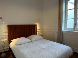 een slaapkamer met een bed met witte lakens en een raam bij Reims Cathédrale Hyper Centre in Reims