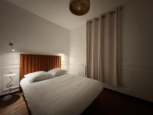 een slaapkamer met een bed met witte lakens en een ventilator bij Reims Cathédrale Hyper Centre in Reims