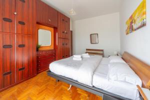 a bedroom with a large white bed and wooden cabinets at "Casa Zenit" 3 minuti Metro & 20 minuti Duomo di Milano in Sesto San Giovanni