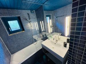 a blue tiled bathroom with a sink and a tub at Chalet Franzi - Ruhiges Chalet mit Bergblick, Garten und gratis Eintritt ins Solarbad in Dorfgastein +35 photos