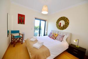 um quarto com uma cama branca e uma cadeira em Vela - Apartment in complex near the beach em São Martinho do Porto