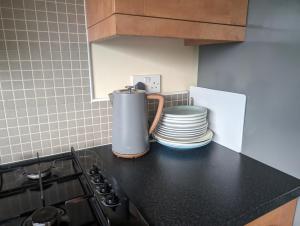 a kitchen counter with a blender and a stack of plates at Dudley Rooms in Tipton