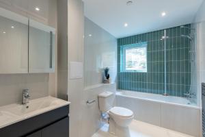 a bathroom with a toilet and a tub and a sink at Deluxe South Central Apartment in London