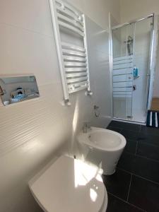 La salle de bains blanche est pourvue d'une douche et de toilettes. dans l'établissement Moderna Casa Fronte Mare, à Cogoleto