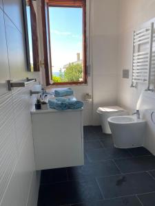 La salle de bains est pourvue d'un lavabo, de toilettes et d'une fenêtre. dans l'établissement Moderna Casa Fronte Mare, à Cogoleto