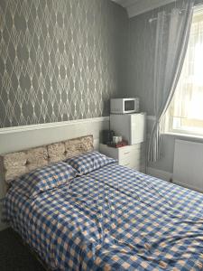 Un dormitorio con una cama con una manta de cuadros azul y blanco en The Majestic en Great Yarmouth