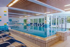 ein großes Schwimmbecken mit Liegestühlen in einem Gebäude in der Unterkunft Hotel Kompas in Kranjska Gora