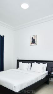 - une chambre avec un grand lit aux murs blancs dans l'établissement SOFT HOTEL, à Douala