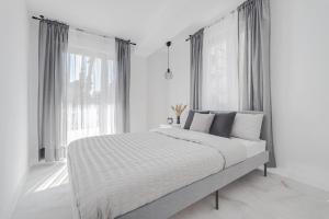 - une chambre blanche avec un grand lit en face des fenêtres dans l'établissement Princesa Blanka by ZANIS, à Torrevieja