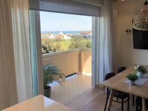 Un comedor con una mesa y una gran puerta corrediza de vidrio. en Appartamento Fronte Mare Sottomarina, en Sottomarina