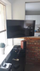 telewizor z płaskim ekranem siedzący na biurku w obiekcie Domek Gościnny nad jeziorem Limajno w Olsztynie