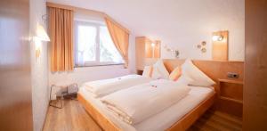 a bedroom with a large white bed with a window at Försterhäusl in Seefeld in Tirol