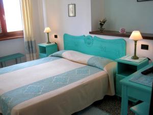 sypialnia z niebieskim łóżkiem z dwoma stołami w obiekcie Hotel Moderno w mieście Santa Teresa Gallura