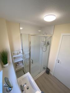 uma casa de banho com um chuveiro e um lavatório branco em Treetops - Bright 2 Bed Flat - Super Location em Inverness
