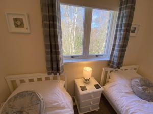 2 camas individuais num quarto com uma janela em Treetops - Bright 2 Bed Flat - Super Location em Inverness