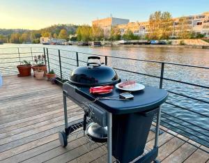een grill op een steiger naast een waterlichaam bij One of the kind Prague Houseboat Experience +BOAT in Praag